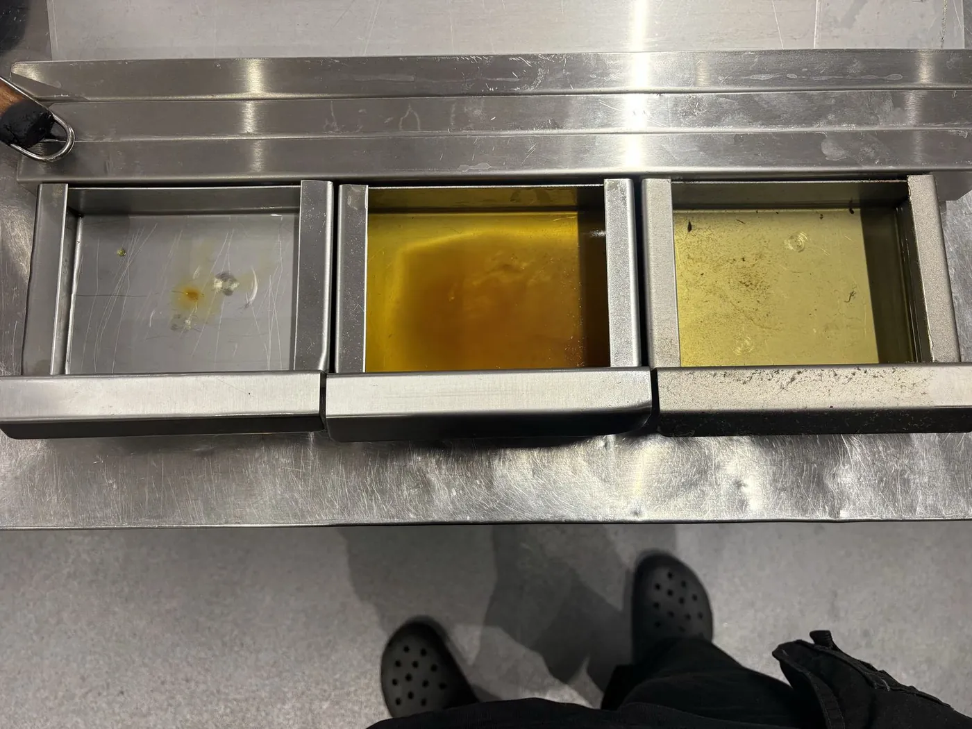 Three kitchen extract filter trays side by side, one clean and two holding accumulated grease